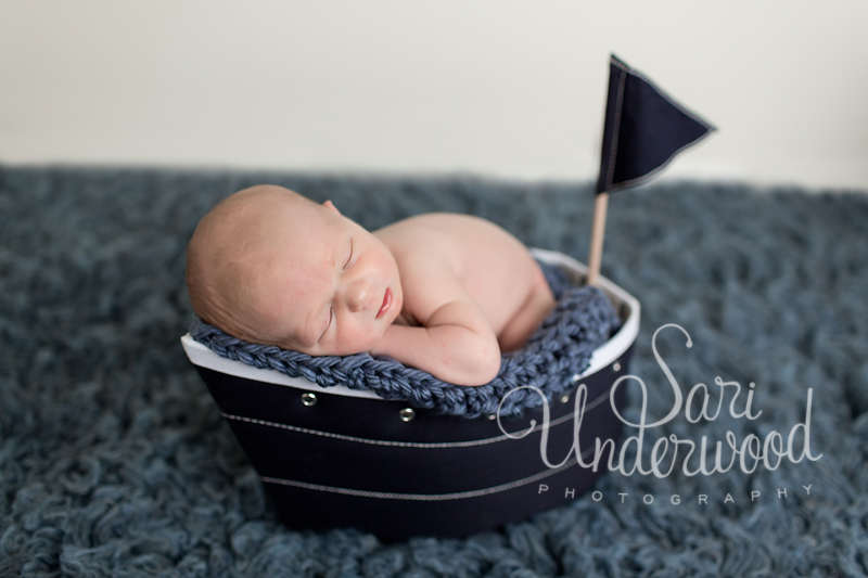 newborn baby boy posed in a little sail boat
