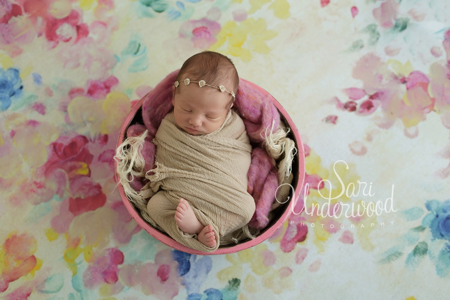 baby girl in a round pink bucket