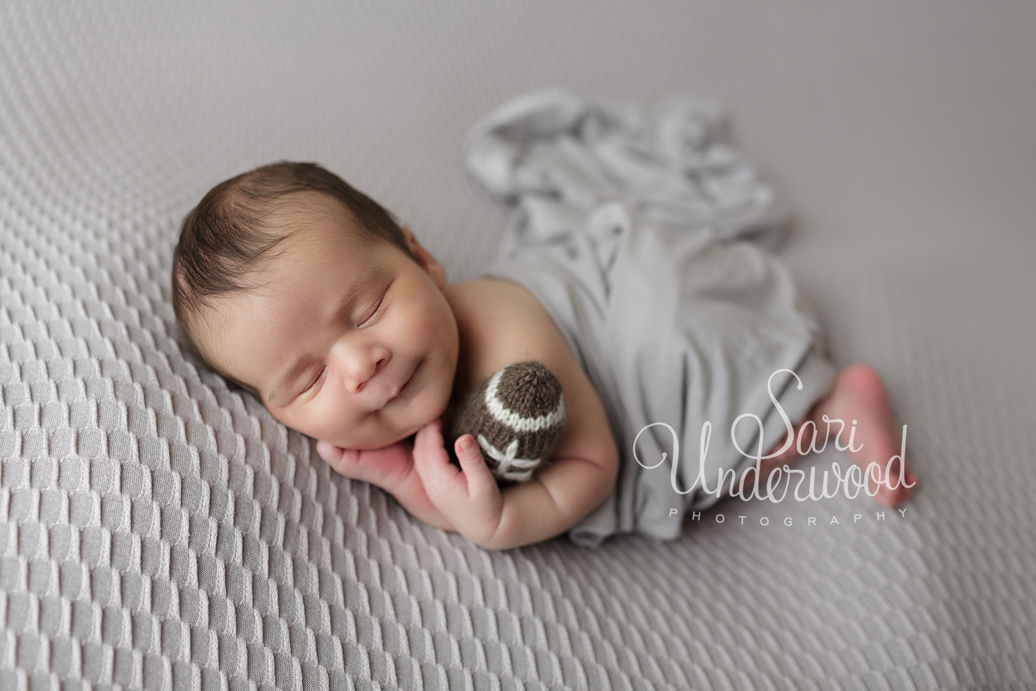 newborn baby boy holding football