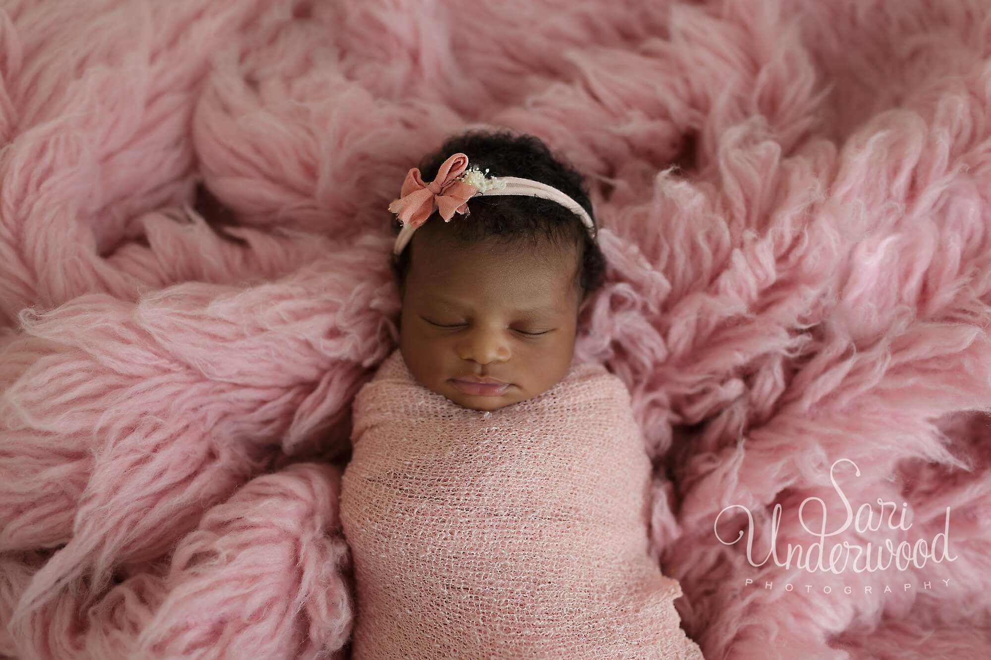 newborn baby girl swaddled in pink