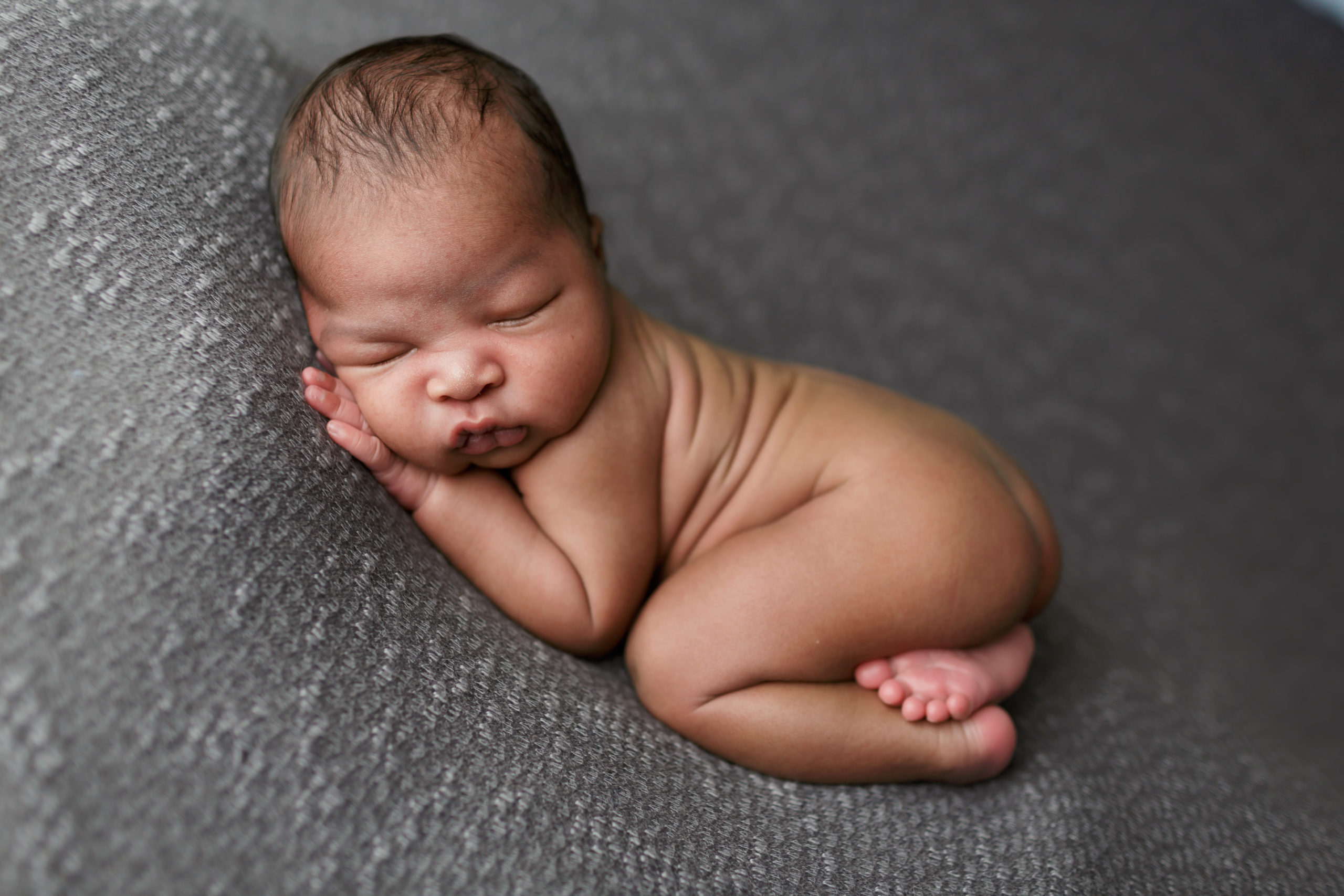 baby boy posed on dark grey blanket