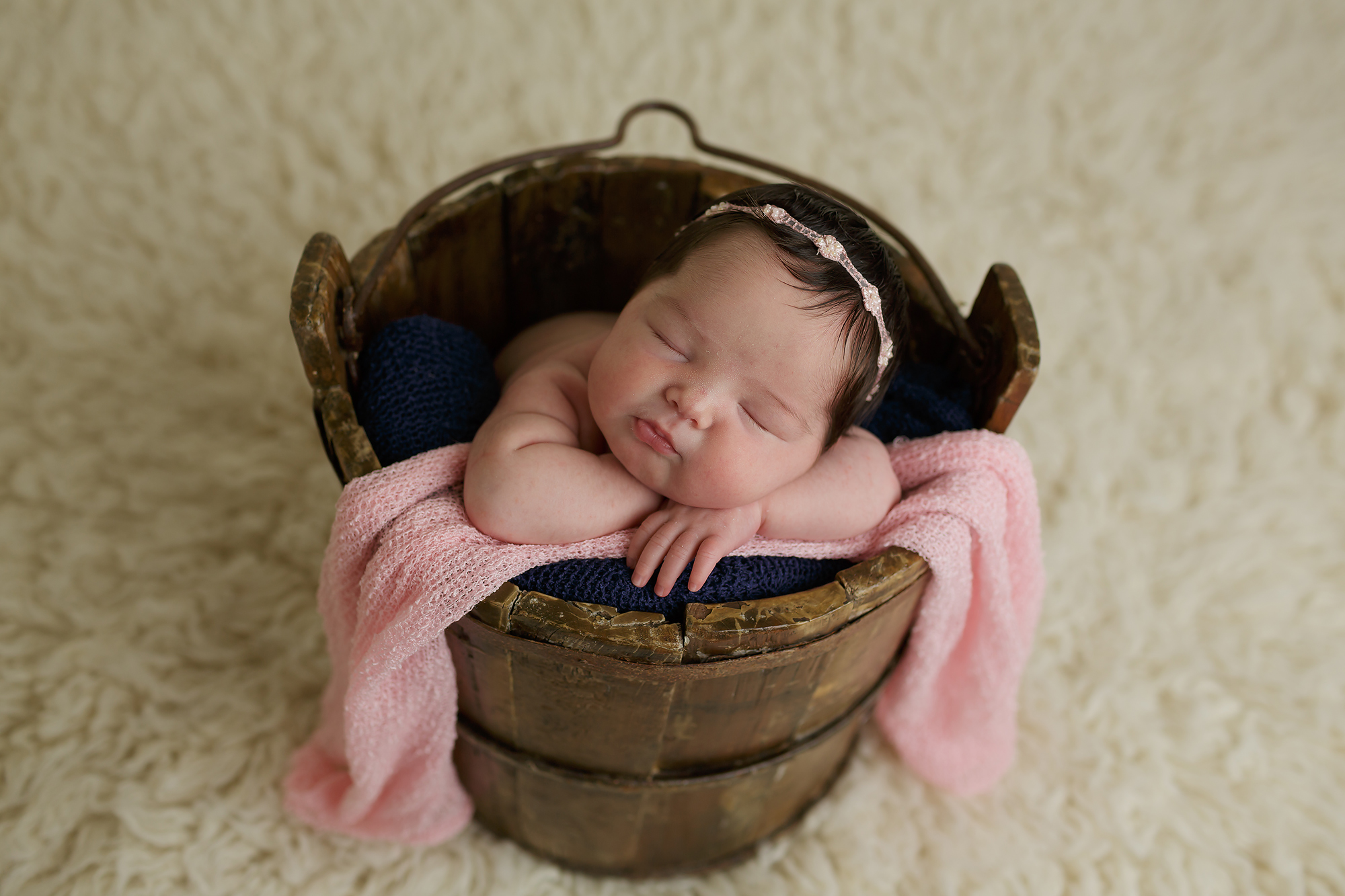 newborn baby posed in wooden bucket