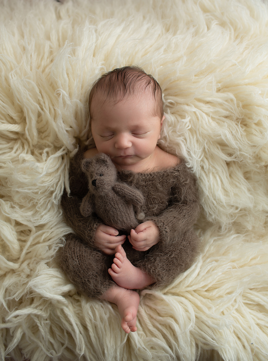 baby boy holding a brown teddy