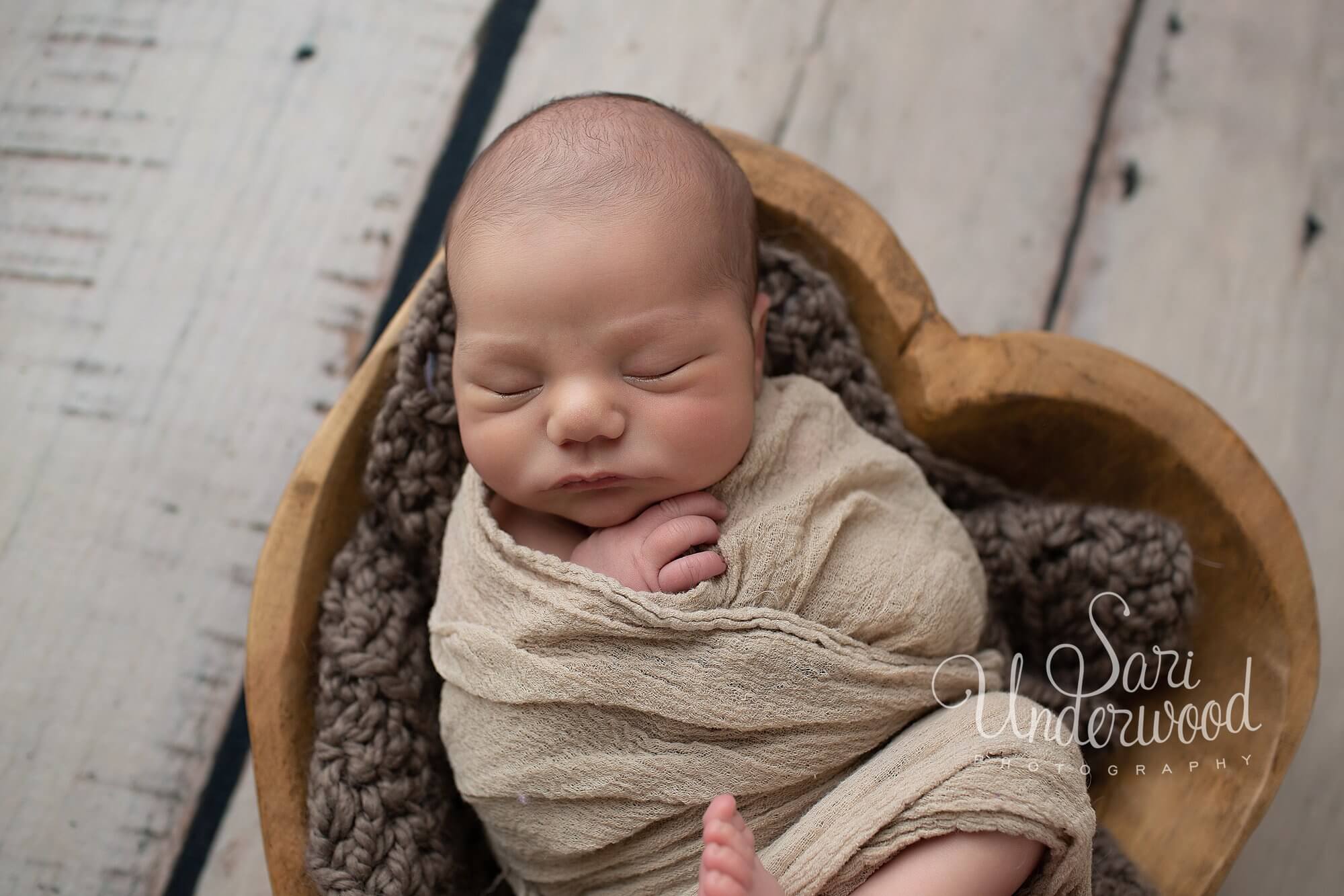 newborn baby boy posed in a heart bowl