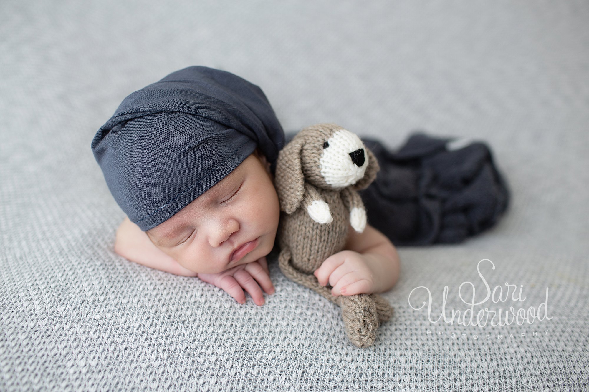 newborn boy holding a dog stuffie