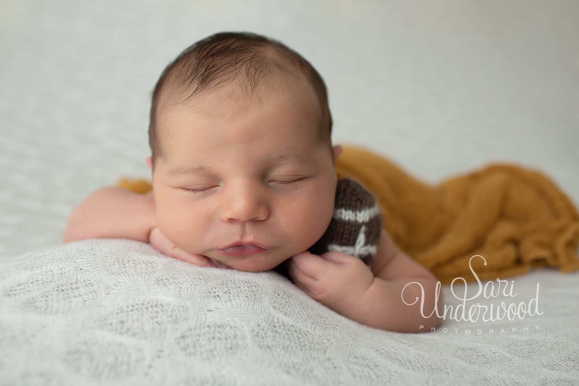 newborn baby boy posed with a tiny knitted football 